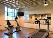 Thumbnail 19 of 33 - A gym with a treadmill and a stationary bike.
