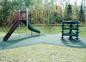 Thumbnail 11 of 21 - A playground with a green slide and a wooden bench.