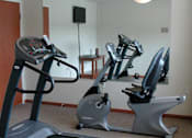 Thumbnail 18 of 21 - A room with a treadmill and a stationary bike.