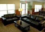 Thumbnail 19 of 21 - Two black leather couches in a room with a table between them.