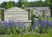Thumbnail 1 of 21 - A sign for Indianhead Cottages with a phone number and address.