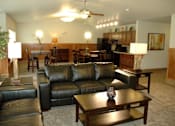 Thumbnail 20 of 21 - A black leather couch sits in a living room with a wooden coffee table in front of it.