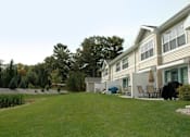 Thumbnail 3 of 18 - A house with a lawn and trees in the background.