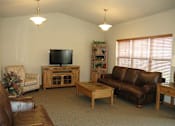 Thumbnail 5 of 18 - A living room with a brown leather couch and a wooden coffee table.