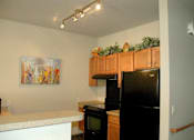 Thumbnail 10 of 18 - A kitchen with a black fridge and a painting on the wall.