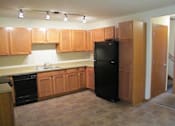 Thumbnail 1 of 18 - A kitchen with wooden cabinets and a black refrigerator.