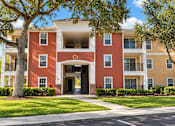 Thumbnail 3 of 14 - A red and beige apartment building with a tree in front.