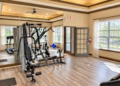 Thumbnail 6 of 14 - A gym with a variety of equipment including a weight bench, a treadmill, and a stationary bike.