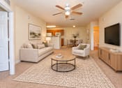 Thumbnail 10 of 14 - A living room with a beige couch, a coffee table, and a ceiling fan.