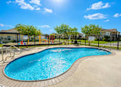 Thumbnail 2 of 21 - A sunny day at a pool with a slide and a playground.