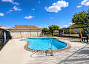 Thumbnail 12 of 21 - A small pool with a brown fence and a blue sky in the background.