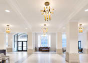 Thumbnail 3 of 8 - A large, well-lit lobby with a chandelier and a bench.