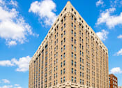 Thumbnail 1 of 8 - A large, beige, rectangular building with many windows and a flat roof.