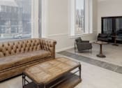 Thumbnail 3 of 5 - A brown tufted sofa sits in a room with a wooden coffee table in front of it.