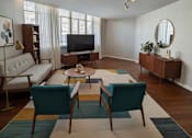 Thumbnail 9 of 12 - A living room with a white couch, a coffee table, and a television.