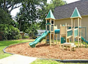 Thumbnail 4 of 5 - A playground with a green slide and wooden structure.