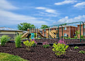 Thumbnail 8 of 14 - A playground with a slide and a green railing is in front of a building.