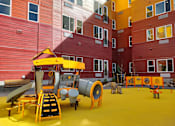 Thumbnail 3 of 5 - A playground with a red, yellow, green and blue arch.