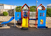 Thumbnail 9 of 9 - A playground with a blue slide and two red and blue houses.