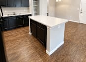 Thumbnail 45 of 46 - A kitchen with black cabinets and a white island.
