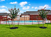 Thumbnail 17 of 46 - Two trees with red flowers stand in front of a pool and a building.