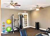 Thumbnail 34 of 46 - A gym room with a variety of equipment including a treadmill, weights, and a bench.