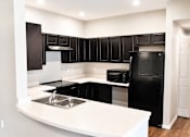 Thumbnail 36 of 46 - A black and white kitchen with a sink and a refrigerator.