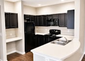 Thumbnail 40 of 46 - A kitchen with black appliances and white countertops.