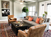 Thumbnail 27 of 46 - A living room with a grey couch, brown leather chairs, and a coffee table.