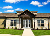 Thumbnail 2 of 46 - A building with a stone facade and a large glass door.