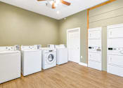Thumbnail 33 of 46 - A room with a row of washing machines on the left and a row of dryers on the right.