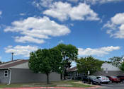 Thumbnail 10 of 16 - A parking lot with cars and a building in the background.