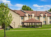Thumbnail 3 of 5 - A tree stands in front of a building with a covered patio.