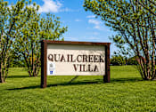 Thumbnail 4 of 5 - A sign that says Quail Creek Villa stands in a grassy field.