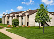 Thumbnail 5 of 5 - A tree stands in front of a building with a walkway in front of it.