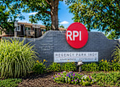 Thumbnail 1 of 17 - A sign for Regency Park Indy apartments is displayed in front of a building.