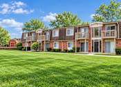 Thumbnail 6 of 17 - A row of red brick apartment buildings with green lawns in front.