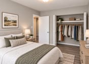 Thumbnail 16 of 17 - A bedroom with a large bed and a closet with clothes.