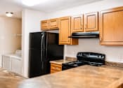 Thumbnail 8 of 14 - A kitchen with black appliances and wooden cabinets.