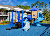 Thumbnail 10 of 14 - A playground with a blue slide and a wooden structure.
