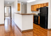 Thumbnail 5 of 14 - A kitchen with a black refrigerator and wooden cabinets.