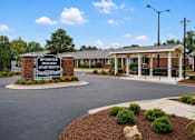 Thumbnail 1 of 9 - A sign for Riverview Heights Apartments stands in front of a building.