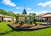 Thumbnail 4 of 9 - A playground with a green slide and a wooden structure with a flag on top.