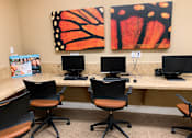 Thumbnail 8 of 9 - A room with a desk and chairs and two paintings on the wall.