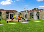 Thumbnail 3 of 4 - A playground with a slide and swings in front of apartment buildings.