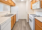 Thumbnail 12 of 23 - A kitchen with white appliances and wooden cabinets.