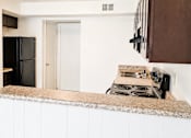 Thumbnail 8 of 9 - A kitchen with a black fridge and stove top oven.