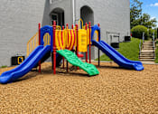 Thumbnail 6 of 9 - A playground with a blue slide and a green slide.