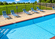 Thumbnail 4 of 9 - A pool surrounded by chairs and a fence.