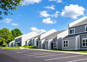 Thumbnail 1 of 9 - A row of modern houses with grey exteriors and white roofs.